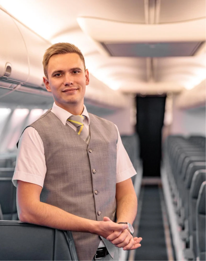 young man airline worker looking camera smiling while leaning passenger seat airplane 1